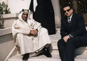 صورة نادرة للملك فيصل جالسًا على درج قصر بالرياض.. والكشف عن تاريخ التقاطها وهوية الشخص الذي ظهر بجانبه