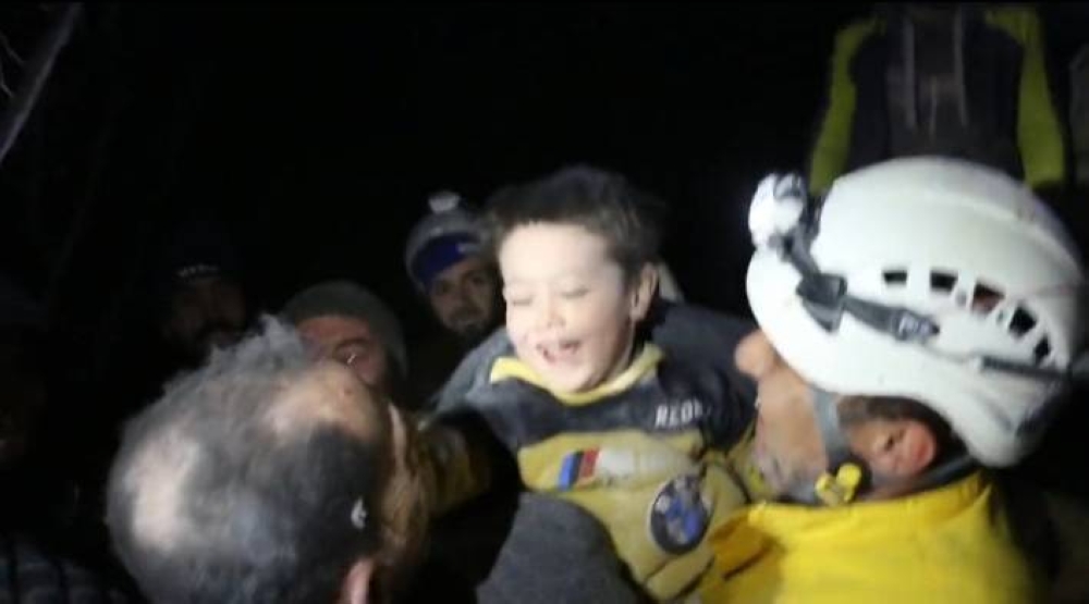 بالفيديو طفل سوري يخرج ضاحكا من أسفل أنقاض منزله ويداعب رجال الإنقاذ